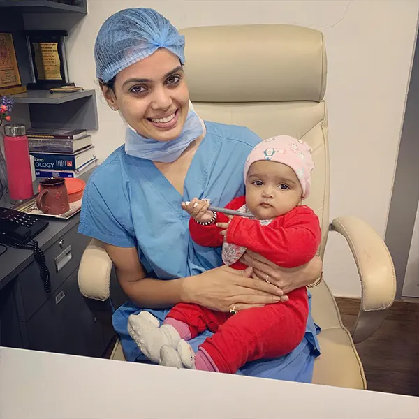 dr ruchi bhandari sitting on chair with baby in hand